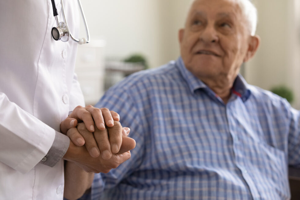 A doctor holding the hand of an elderly patient